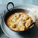 عکسی از غذای خورش مرغ و کاری است. یک ظرف که درون آن به اندازه 5 قاشق غذا خوری برنج است. کنار برنج ها کاسه ای از خورشت مرغ و کاری قرار دارد. طرز تهیه خورش کاری با ماست