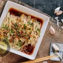 عکسی است از یک ظرف سفید عذای قارچ انوکی با سس سیر و پیازچه