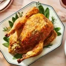 عکسی از یک دیس سفید که در آن یک مرغ شکم پر کامل قرار دارد. طرز تهیه مرغ شکم پر با قارچ
